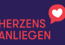 Auf dunkelblauem Hintergrund steht in Versalen in roter SChrift HERZENS ANLIEGEN und oben rechts ist eine rote Sprechblase mit einem weißen Herz abgebildet